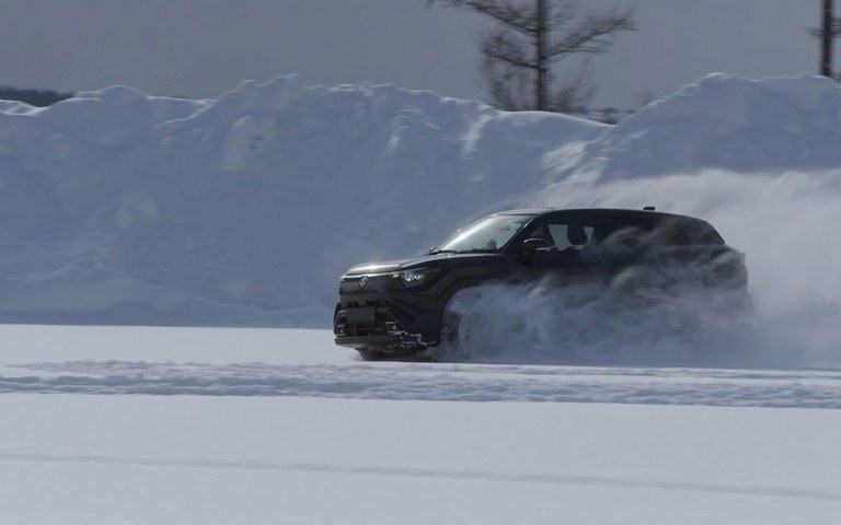 Grüner Suzuki e Vitara fährt auf schneebedeckter Straße durch Winterlandschaft Grüner Suzuki e Vitara fährt auf schneebedeckter Straße durch Winterlandschaft