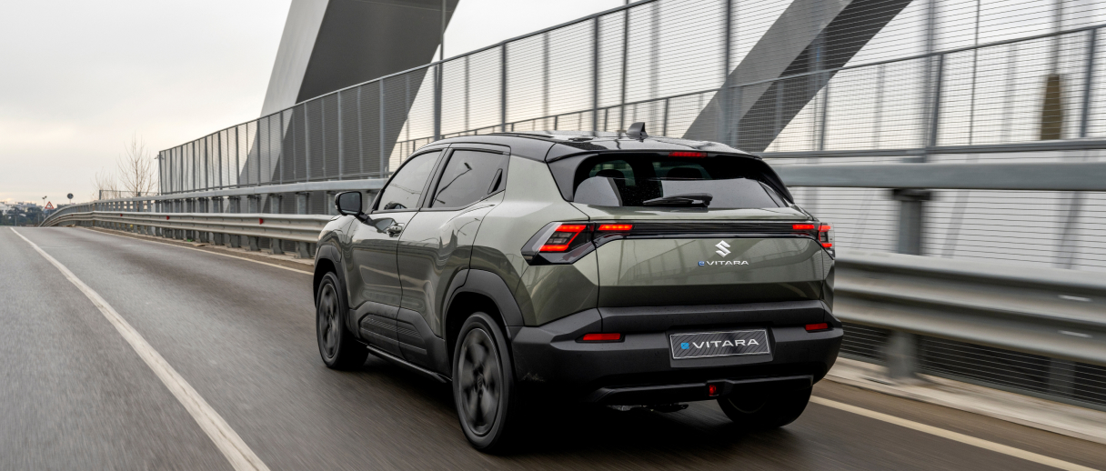 Grüner Suzuki e VITARA fährt über eine Brücke