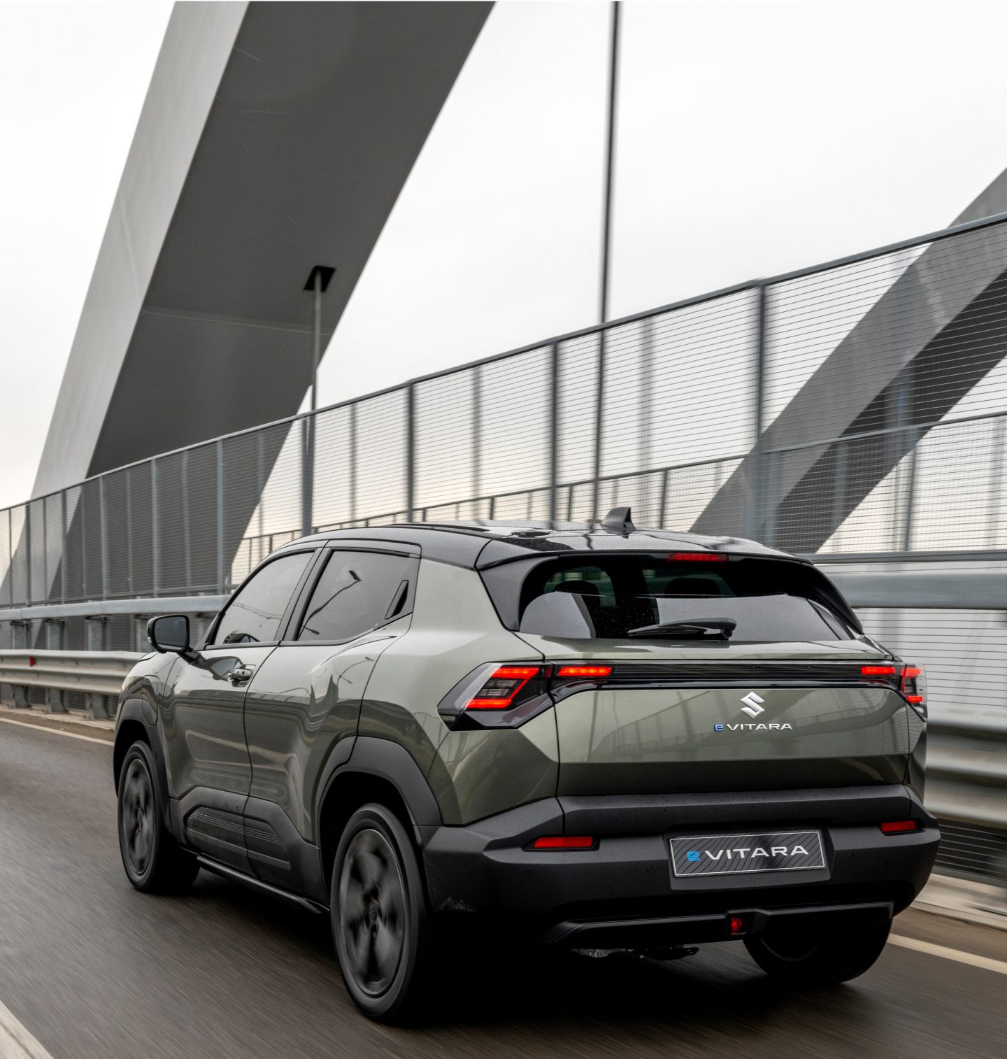 Grüner Suzuki e VITARA fährt über eine Brücke