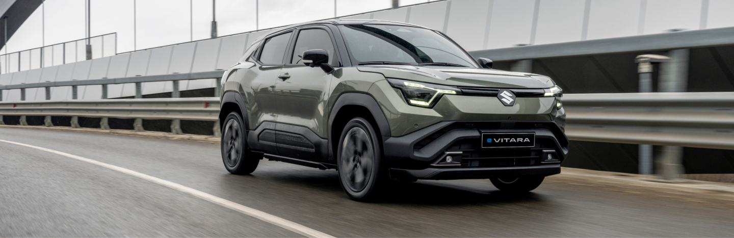 Grüner Suzuki e VITARA fährt über eine Brücke