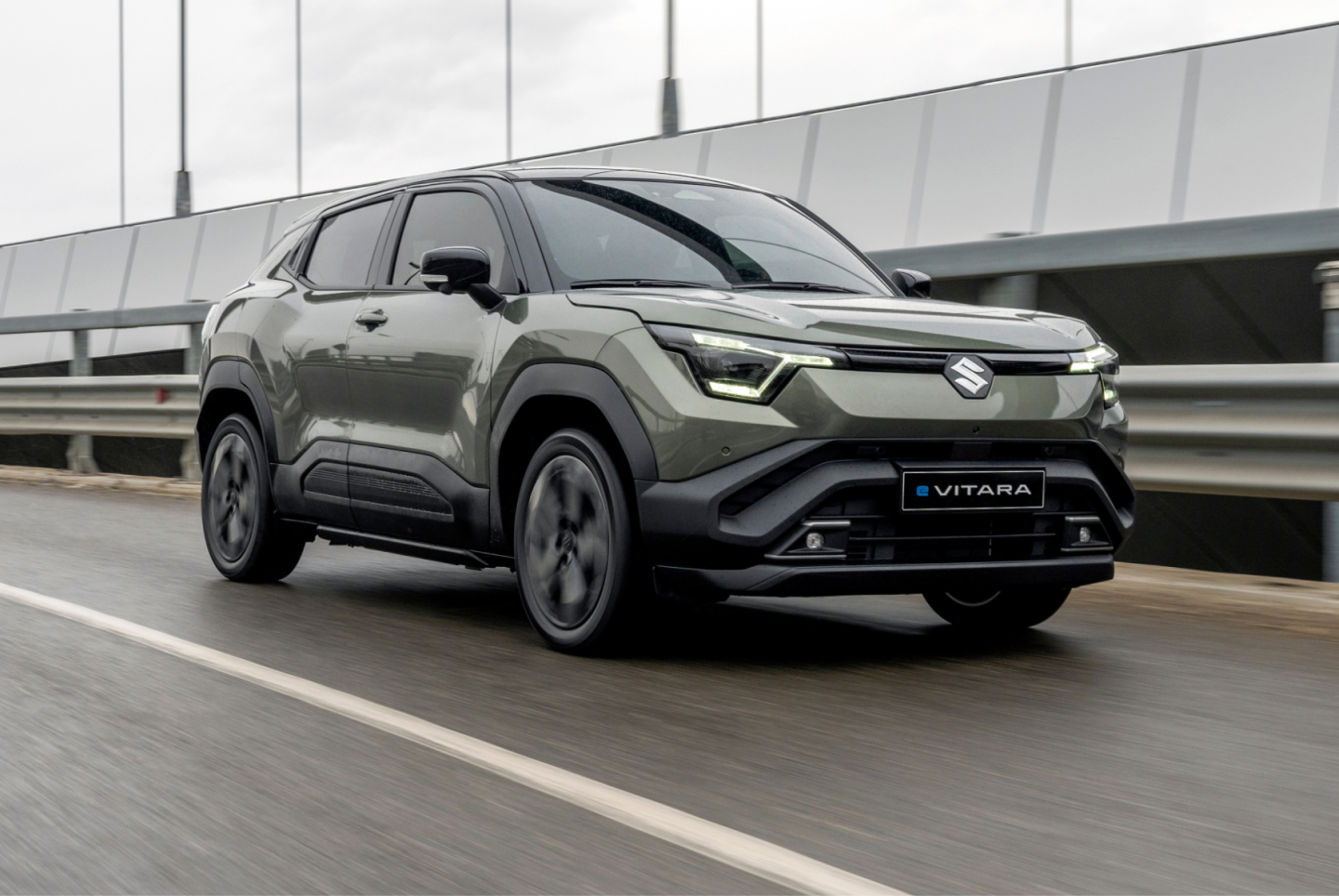 Grüner Suzuki e VITARA fährt über eine Brücke
