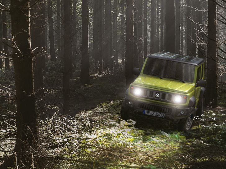 Suzuku Jimny Hybrid in Kinetic Yellow fährt durch den Wald.